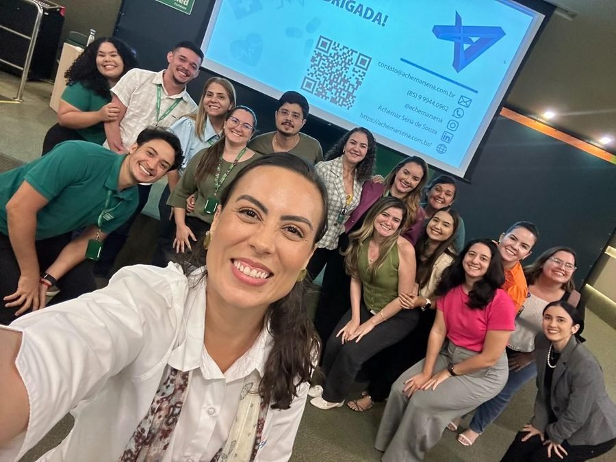 Equipe ao final de um treinamento, com a apresentação ao fundo
